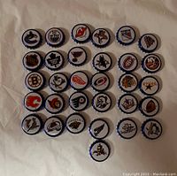 Photo of 31 Labatt's beer caps each featuring a different NHL team logo arranged on a white cloth.