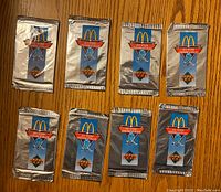 Front view of eight sealed 1991-92 McDonald’s Upper Deck NHL hockey card packs on wooden surface.