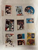 Top view of all nine Wayne Gretzky hockey cards and stickers laid out on white surface, showing front side with images and player photos.