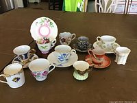 Set of 11 vintage demitasse cups and 6 saucers arranged on table, displaying variety of styles and patterns.