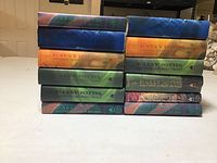 Stack of 12 hardback Harry Potter books showing spine titles including all series books.