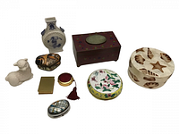 Various vintage trinket boxes, decorative items and a porcelain lamb figurine arranged on white background.