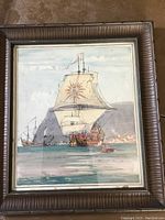 Frontal view of the framed watercolor painting showing two historic sailing ships near a coastal town, highlighting the sail with sun emblem and overall composition.