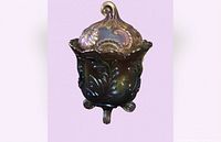 Front view of vintage black amethyst Imperial Glass candy dish with decorative lid showing floral patterns and scroll handle.
