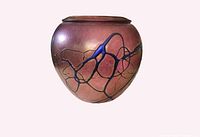 Full frontal view of the pink iridescent rounded vase decorated with blue swirls