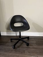Front view of the black modern desk chair showing seat and base with wheels.