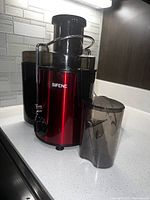 SIFENE red electric juicer with juice container and pulp collector, placed on kitchen countertop.