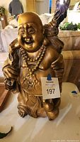 Front view of bronze Laughing Buddha statue showing facial expression, beaded necklace, and emblem on belly.