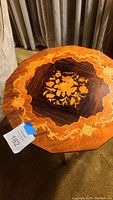 Octagonal table top showing detailed floral marquetry in multiple wood tones.
