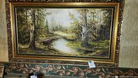 Full view of framed oil painting depicting forest scene with pond