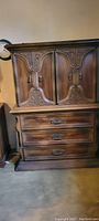 Full view of the front of the dresser showcasing the carved butterfly doors and three drawers beneath.