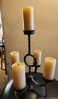 Wrought iron 5-arm candelabra with twisted iron design and five cream candles in place.