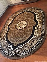 Full view of the oval area rug showing central medallion and border design.