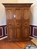 Front view of closed wooden bar cabinet with paneled doors and metal handles