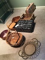 Group of five baskets and two decorative paper boxes arranged on carpeted floor