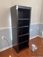Full view of the bookcase showing five shelves, visible damage on the third shelf and wear on other shelves and edges.