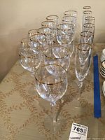 Photo showing 17 Lenox stemware glasses, including champagne flutes and red wine glasses, all with gold rims and textured stems.