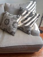 Close-up view of two decorative pillows with beige and black circular pattern on beige sofa upholstery.