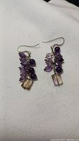 Photo of amethyst dangling earrings showing multiple purple stones and a large rectangular one on each earring.