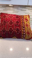 Front view of antique kalim pillow with red and burgundy horizontal stripes alongside gold and cream sections with geometric floral motifs.