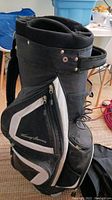 Side view of black and white Tommy Armour golf cart bag showing zippered compartments and Tommy Armour logo.