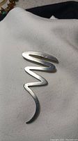 Front of vintage zig zag silver pin/pendant, showing polished abstract zig zag metal design.