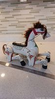 Full view of the wooden horse marionette puppet showing painted floral decorations and real horse hair mane and tail, with a ruler for size reference.