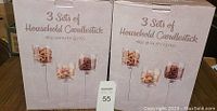 Two large boxes each labeled containing 3 sets of household candlesticks made of high quality glass. Boxes show images of the candlesticks filled with decorative items.