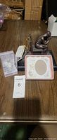 Full view of the three items on a table: birthstone angel, pink picture frame, bronze scripture sculpture