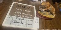 Photo showing framed wooden Family Love sign with text and cheetah figurine next to it on table.