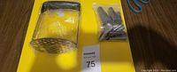 Yellow heavy duty cutting board with a stainless steel potato masher and a sealed plastic bag containing metal tips or accessories on top.