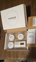 Opened box showing three Thovas smart lighting units and Duracell batteries inside their packaging.