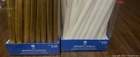 Photo of two unopened boxes of menorah candles, one gold and one white, each containing 44 candles.