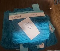 Stack of ten blue fluffy zip pouches with Yoobi branding and tags visible.