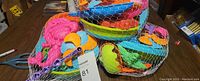 Set of three new sealed plastic sand toys in netting on a wooden surface.