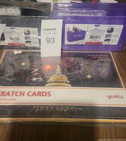 Photo showing two plastic pencil holders (black and purple) and a package of scratch cards with fireworks design.