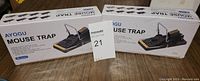 Two unopened boxes of AYOGU mouse traps on wooden surface with lot number.