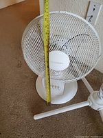 Photo showing white table fan with measuring tape indicating fan height approximately 12 inches