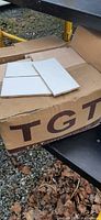 Photo showing white ceramic subway tiles placed on a cardboard box with partial brand name visible.