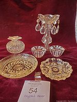 Full view of the crystal decor lot on a red surface, showing all items including candle holders, trinket box, and plates