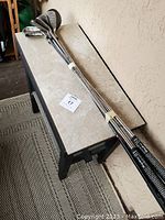 Photo showing multiple golf clubs lined up on a table against a wall, showing their shafts and grips.