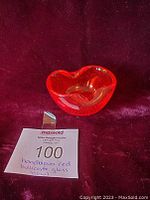 Red Bullicante art glass bowl showing heart-like shape, internal tiny bubbles, and shiny surface on red velvet background.