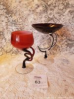 Shows both Krosno glass bowls, one amethyst purple with a clear twisted stem and one cased red swirl bowl, positioned side by side on a lace background.