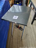 Top view of gray textured metal folding table with three tubular metal legs visible, showing condition and size.