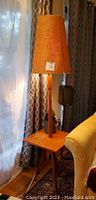 Full view of teak side table lamp showing square top, central lamp column, conical shade and splayed legs.