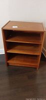 Front view of teak veneer cabinet showing three shelves and open front