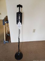 Full length photo of metal detector showing adjustable silver metal stem, circular black search coil at bottom, and black control box at upper part.
