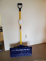 Full view of the snow shovel showing the yellow handle with D-grip and blue blade with metal edge