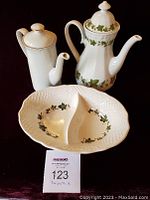 Photo showing two ceramic teapots and a divided oval serving bowl with ivy leaf pattern on a dark background.