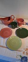 Full set of vintage Fiesta Ware on a table including three plates, two cups, creamer, and gravy boat.